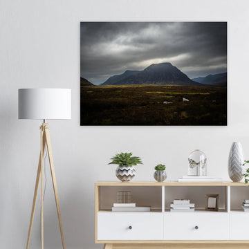 Buachaille Etive Mòr stormy sunrise wall art showing the dark Glencoe mountain under heavy clouds with a strip of light over the foreground moorland