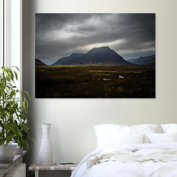Buachaille Etive Mòr stormy sunrise wall art showing the dark Glencoe mountain under heavy clouds with a strip of light over the foreground moorland