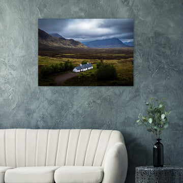 Blackrock Cottage Buachaille Etive Mòr wall art showing the white cottage in front of a dramatic Scottish Highlands mountain under dark storm clouds and moody light