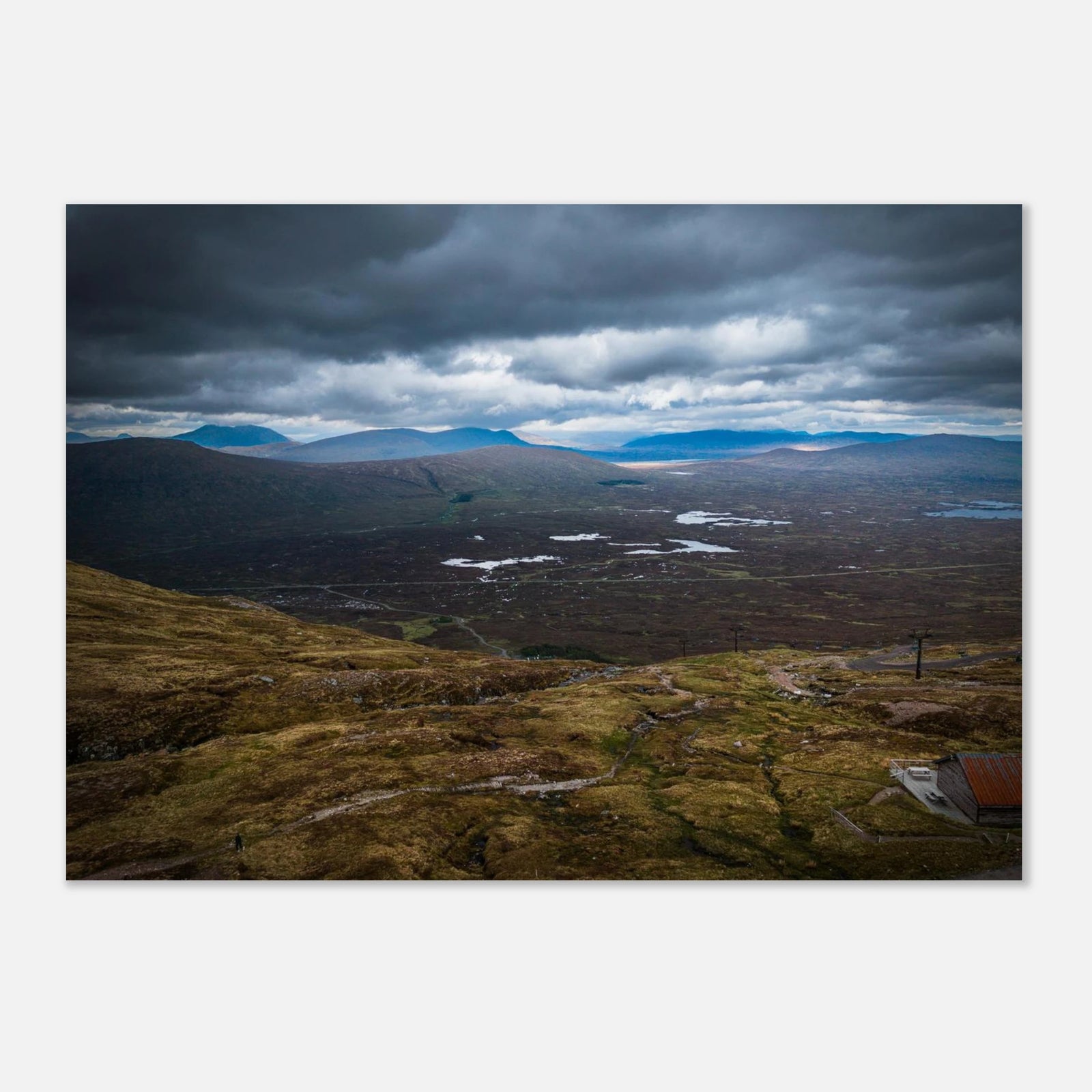 Glencoe Valley From Above wall art showing a wide Highland moor with distant blue hills, scattered lochans and heavy clouds over the Glencoe landscape