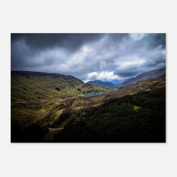 Scottish Highlands Glen wall art showing a rugged valley with rolling heather hills, a small loch and heavy storm clouds over the remote Scottish landscape