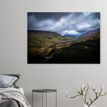 Scottish Highlands Glen wall art showing a rugged valley with rolling heather hills, a small loch and heavy storm clouds over the remote Scottish landscape