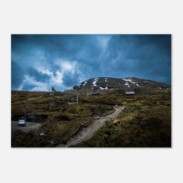 Glencoe Ski Lift wall art showing empty chairlifts climbing a rugged hillside towards snow patches with dramatic blue-grey clouds over Glencoe Mountain Resort