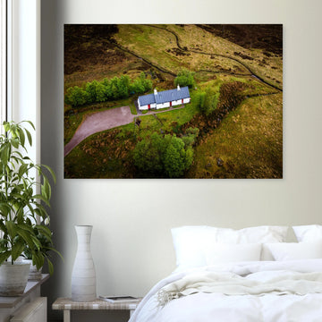 Blackrock Cottage Glencoe wall art showing an aerial view of the long white cottage with red doors surrounded by green moorland, trees and winding tracks