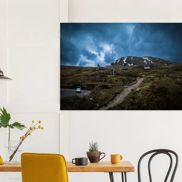 Glencoe Ski Lift wall art showing empty chairlifts climbing a rugged hillside towards snow patches with dramatic blue-grey clouds over Glencoe Mountain Resort