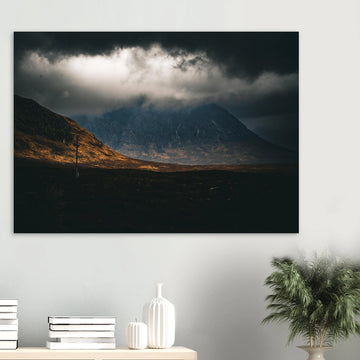Glencoe sunrise wall art showing Buachaille Etive Mòr under dark storm clouds with a strip of warm light across the foreground moorland