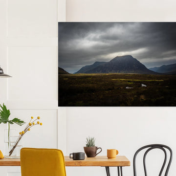 Buachaille Etive Mòr stormy sunrise wall art showing the dark Glencoe mountain under heavy clouds with a strip of light over the foreground moorland