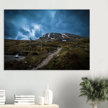 Glencoe Ski Lift wall art showing empty chairlifts climbing a rugged hillside towards snow patches with dramatic blue-grey clouds over Glencoe Mountain Resort