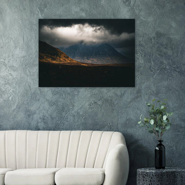 Glencoe sunrise wall art showing Buachaille Etive Mòr under dark storm clouds with a strip of warm light across the foreground moorland