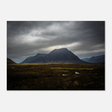 Buachaille Etive Mòr stormy sunrise wall art showing the dark Glencoe mountain under heavy clouds with a strip of light over the foreground moorland