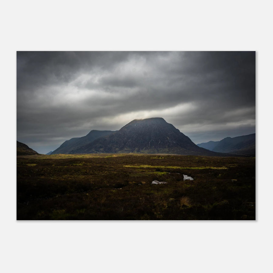 Buachaille Etive Mòr stormy sunrise wall art showing the dark Glencoe mountain under heavy clouds with a strip of light over the foreground moorland