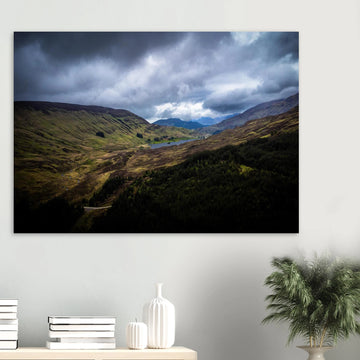 Scottish Highlands Glen wall art showing a rugged valley with rolling heather hills, a small loch and heavy storm clouds over the remote Scottish landscape