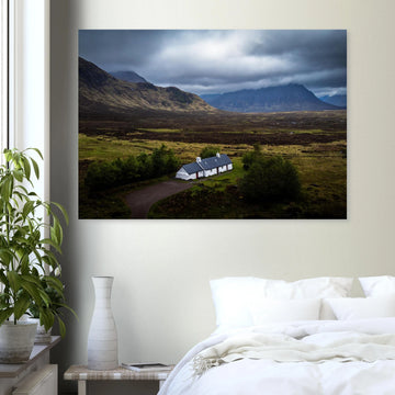 Blackrock Cottage Buachaille Etive Mòr wall art showing the white cottage in front of a dramatic Scottish Highlands mountain under dark storm clouds and moody light