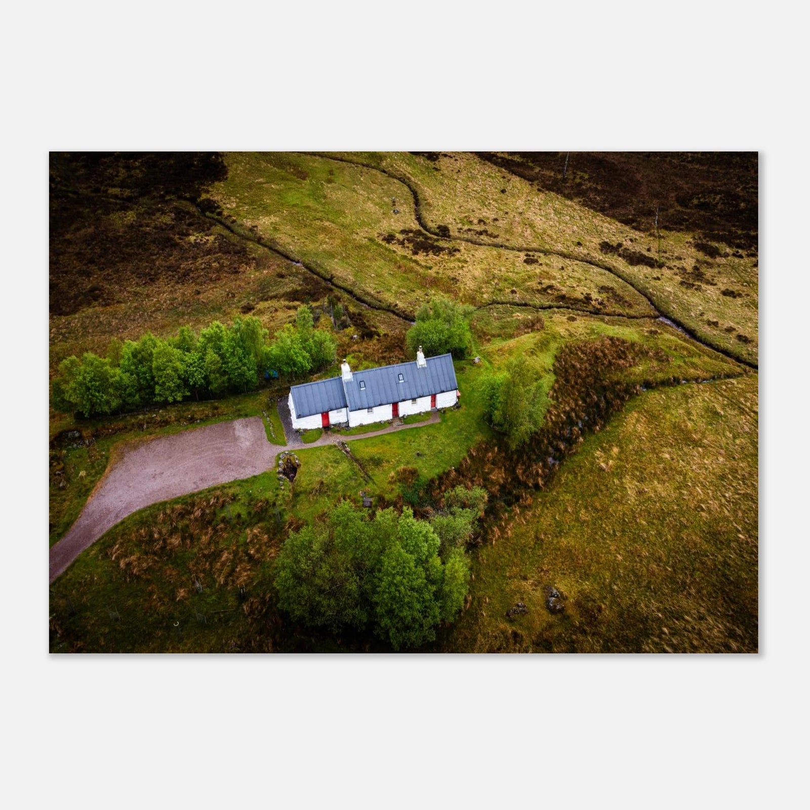Blackrock Cottage Glencoe wall art showing an aerial view of the long white cottage with red doors surrounded by green moorland, trees and winding tracks