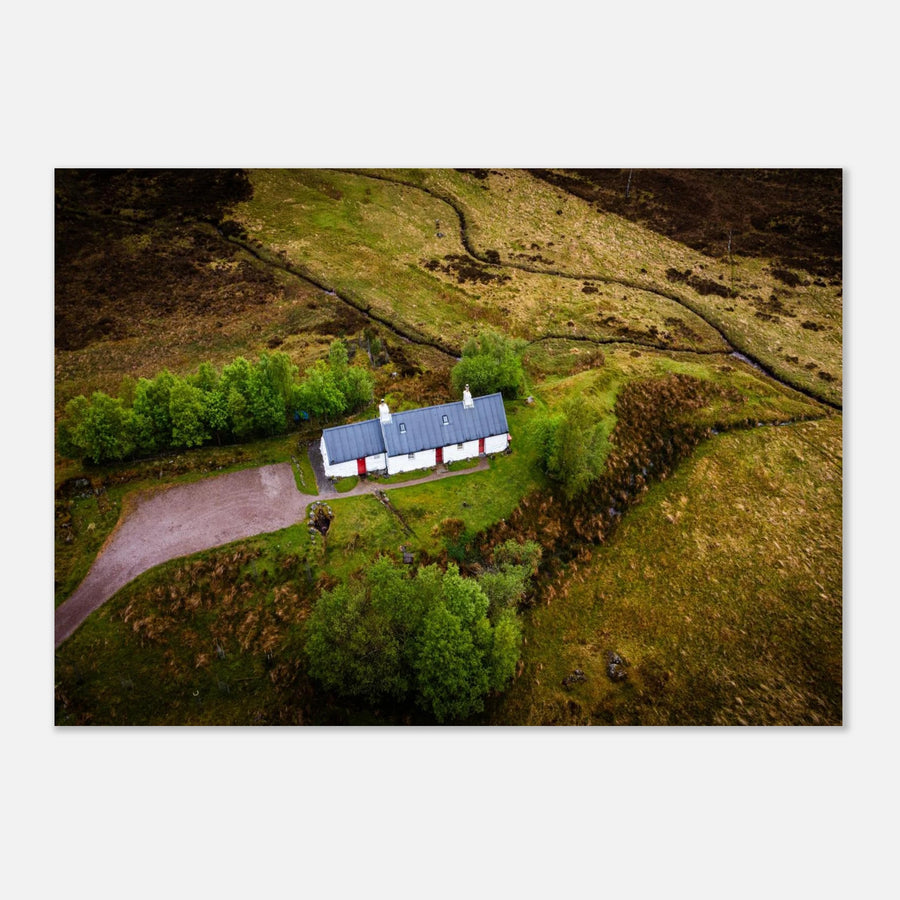 Blackrock Cottage Glencoe wall art showing an aerial view of the long white cottage with red doors surrounded by green moorland, trees and winding tracks