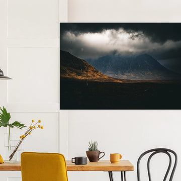 Glencoe sunrise wall art showing Buachaille Etive Mòr under dark storm clouds with a strip of warm light across the foreground moorland
