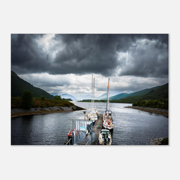 Ballachulish Harbour wall art showing yachts lined up along a narrow pier between green hills with dark storm clouds over the Scottish waterway