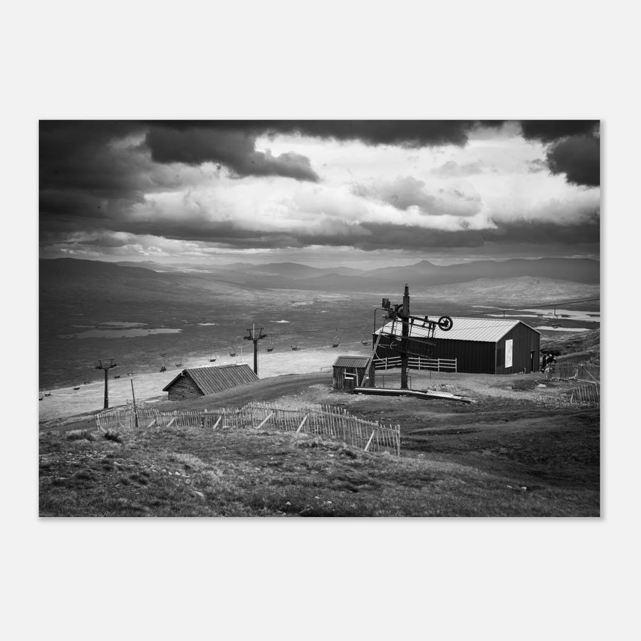 Glencoe Mountain View wall art showing a black and white panorama from Glencoe Mountain with ski lifts, small huts and a wide Highland landscape under dramatic clouds