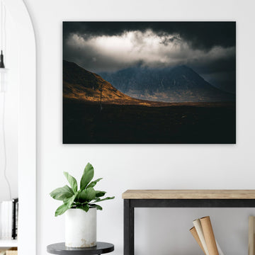 Glencoe sunrise wall art showing Buachaille Etive Mòr under dark storm clouds with a strip of warm light across the foreground moorland