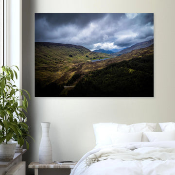Scottish Highlands Glen wall art showing a rugged valley with rolling heather hills, a small loch and heavy storm clouds over the remote Scottish landscape