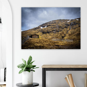 Glencoe Mountain Ski Lift Top wall art showing a wooden hut and fences on a rocky hillside with ski lift towers, snow patches and grey clouds at Glencoe Mountain Resort