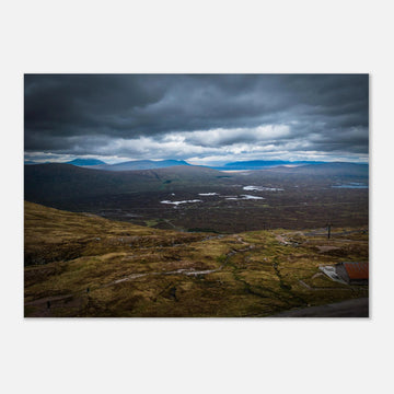 Glencoe Valley From Above wall art showing a wide Highland moor with distant blue hills, scattered lochans and heavy clouds over the Glencoe landscape