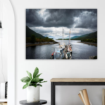 Ballachulish Harbour wall art showing yachts lined up along a narrow pier between green hills with dark storm clouds over the Scottish waterway