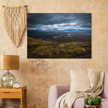 Glencoe Valley From Above wall art showing a wide Highland moor with distant blue hills, scattered lochans and heavy clouds over the Glencoe landscape