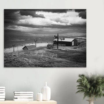 Glencoe Mountain View wall art showing a black and white panorama from Glencoe Mountain with ski lifts, small huts and a wide Highland landscape under dramatic clouds