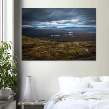 Glencoe Valley From Above wall art showing a wide Highland moor with distant blue hills, scattered lochans and heavy clouds over the Glencoe landscape