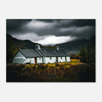 Blackrock Cottage Glencoe wall art featuring an iconic white Highland cottage beneath dark storm clouds and dramatic mountain scenery