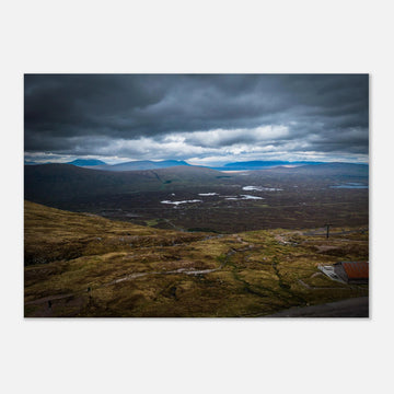 Glencoe Valley From Above wall art showing a wide Highland moor with distant blue hills, scattered lochans and heavy clouds over the Glencoe landscape
