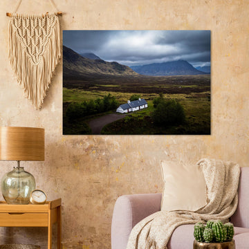 Blackrock Cottage Buachaille Etive Mòr wall art showing the white cottage in front of a dramatic Scottish Highlands mountain under dark storm clouds and moody light