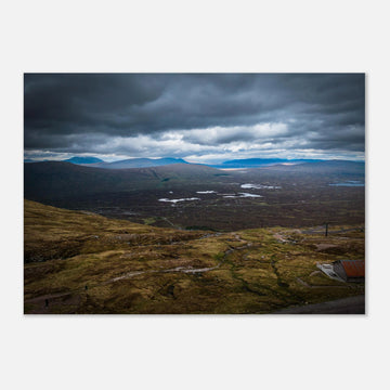 Glencoe Valley From Above wall art showing a wide Highland moor with distant blue hills, scattered lochans and heavy clouds over the Glencoe landscape