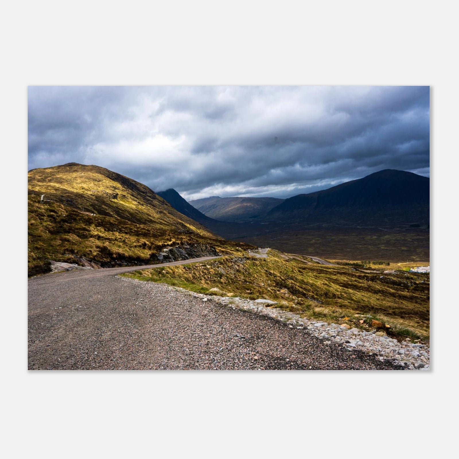 Glencoe Valley wall art showing a winding road from Glencoe Mountain Resort with golden hills, dark mountains and a dramatic cloudy sky over the Highland valley