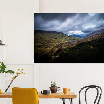 Scottish Highlands Glen wall art showing a rugged valley with rolling heather hills, a small loch and heavy storm clouds over the remote Scottish landscape