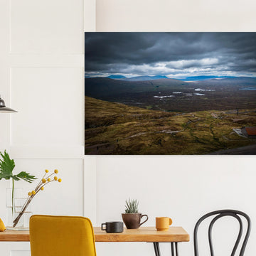 Glencoe Valley From Above wall art showing a wide Highland moor with distant blue hills, scattered lochans and heavy clouds over the Glencoe landscape