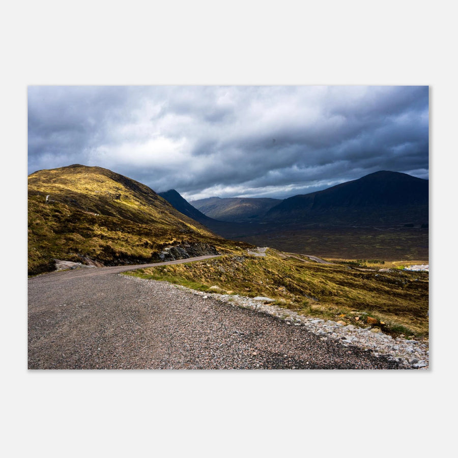 Glencoe Valley wall art showing a winding road from Glencoe Mountain Resort with golden hills, dark mountains and a dramatic cloudy sky over the Highland valley