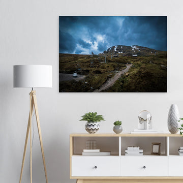 Glencoe Ski Lift wall art showing empty chairlifts climbing a rugged hillside towards snow patches with dramatic blue-grey clouds over Glencoe Mountain Resort