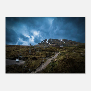 Glencoe Ski Lift wall art showing empty chairlifts climbing a rugged hillside towards snow patches with dramatic blue-grey clouds over Glencoe Mountain Resort
