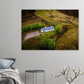 Blackrock Cottage Glencoe wall art showing an aerial view of the long white cottage with red doors surrounded by green moorland, trees and winding tracks