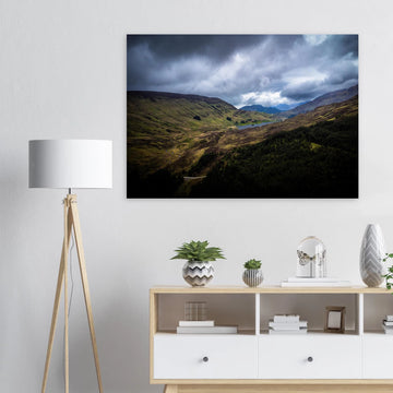 Scottish Highlands Glen wall art showing a rugged valley with rolling heather hills, a small loch and heavy storm clouds over the remote Scottish landscape