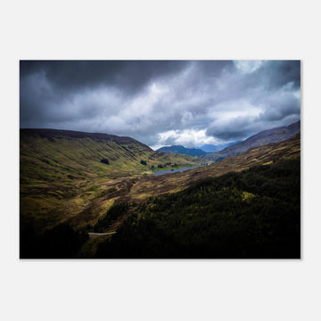 Scottish Highlands Glen wall art showing a rugged valley with rolling heather hills, a small loch and heavy storm clouds over the remote Scottish landscape