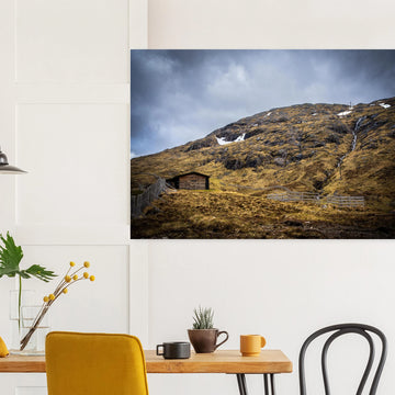 Glencoe Mountain Ski Lift Top wall art showing a wooden hut and fences on a rocky hillside with ski lift towers, snow patches and grey clouds at Glencoe Mountain Resort
