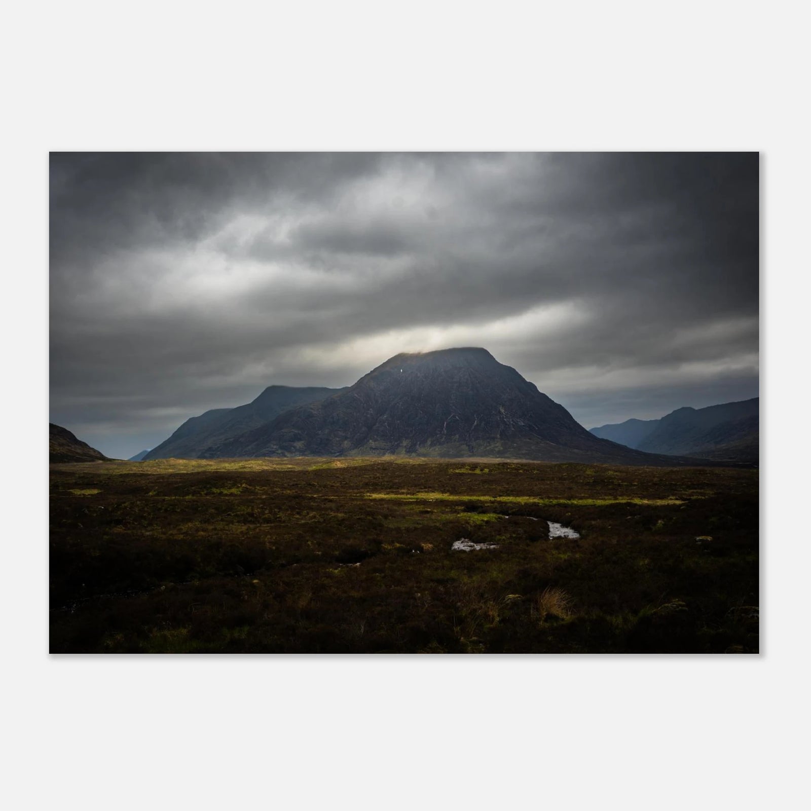Buachaille Etive Mòr stormy sunrise wall art showing the dark Glencoe mountain under heavy clouds with a strip of light over the foreground moorland