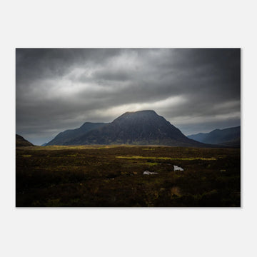 Buachaille Etive Mòr stormy sunrise wall art showing the dark Glencoe mountain under heavy clouds with a strip of light over the foreground moorland