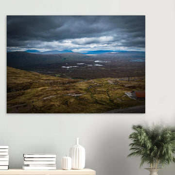 Glencoe Valley From Above wall art showing a wide Highland moor with distant blue hills, scattered lochans and heavy clouds over the Glencoe landscape