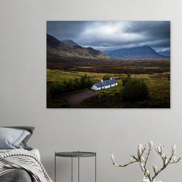 Blackrock Cottage Buachaille Etive Mòr wall art showing the white cottage in front of a dramatic Scottish Highlands mountain under dark storm clouds and moody light