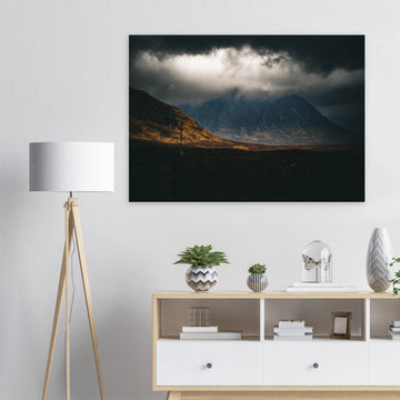 Glencoe sunrise wall art showing Buachaille Etive Mòr under dark storm clouds with a strip of warm light across the foreground moorland