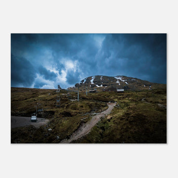 Glencoe Ski Lift wall art showing empty chairlifts climbing a rugged hillside towards snow patches with dramatic blue-grey clouds over Glencoe Mountain Resort